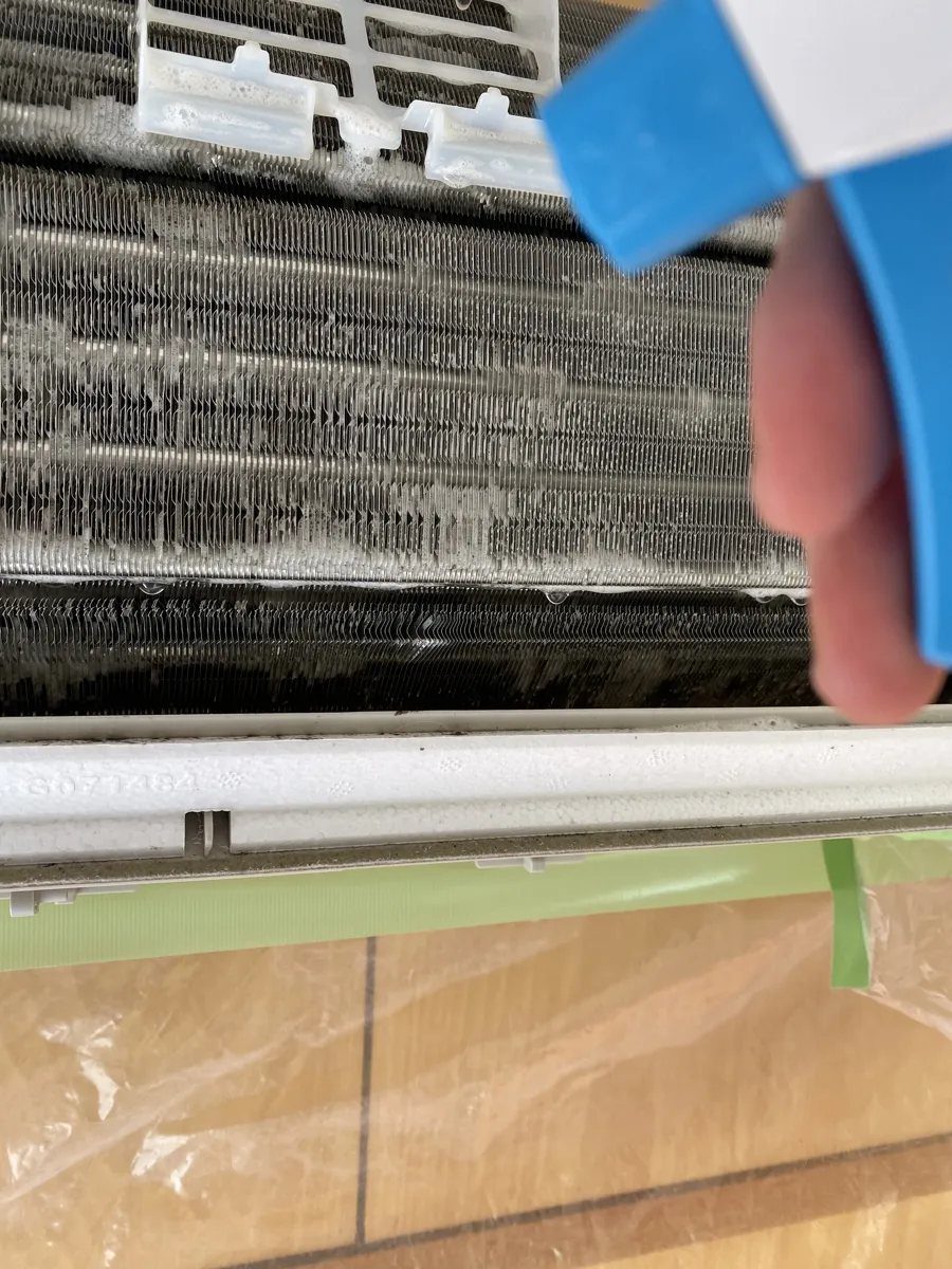 専用洗浄剤をエアコンのアルミフィンに噴霧している様子