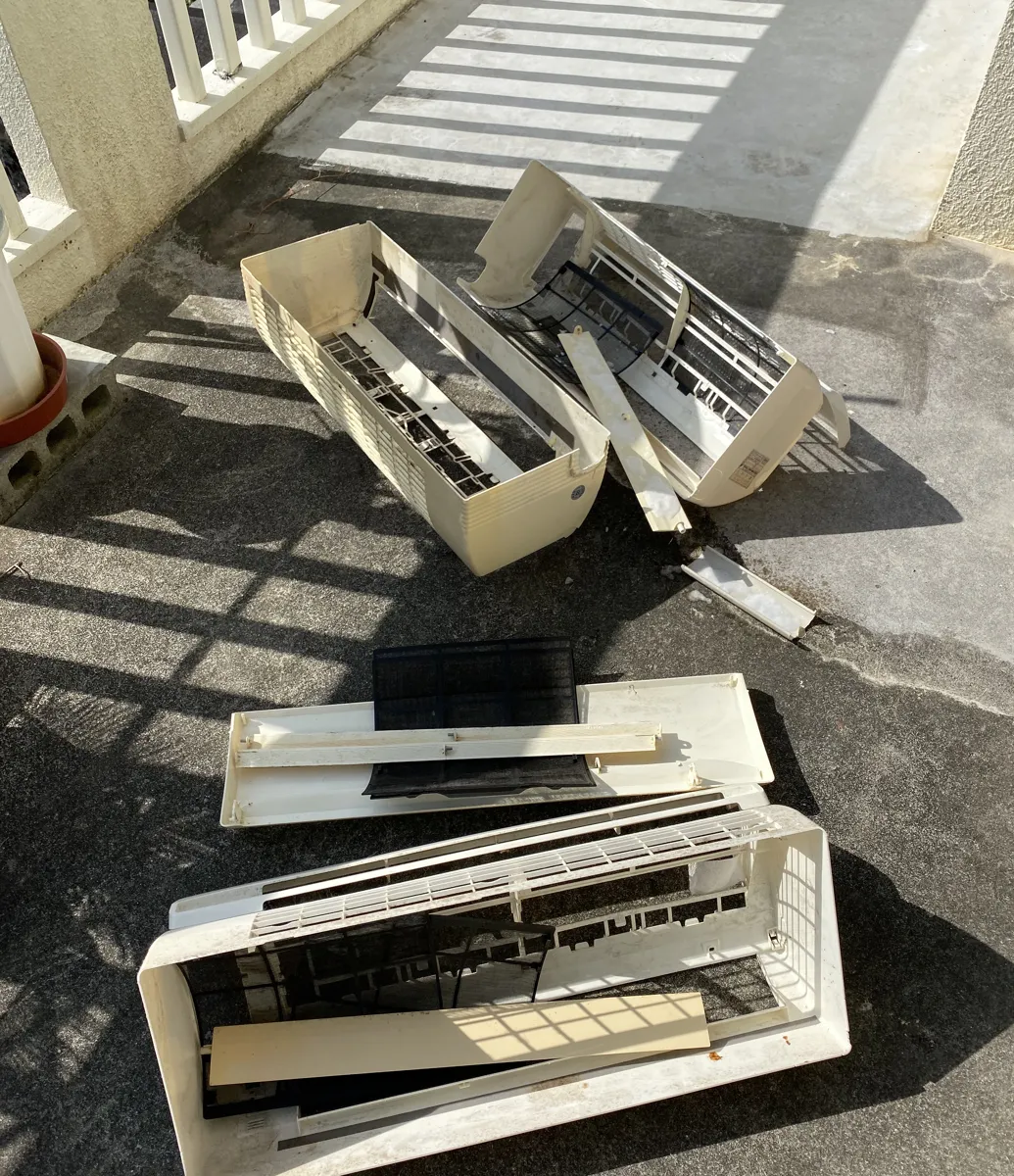 分解したエアコンの外装パーツを屋外で洗浄